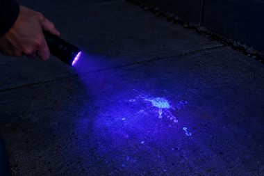 UV Flashlight Illuminating Glowing Pavement Stain